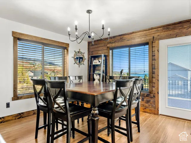 Wood-finish flooring, accent wood paneling, wood window trim, and a black chandelier