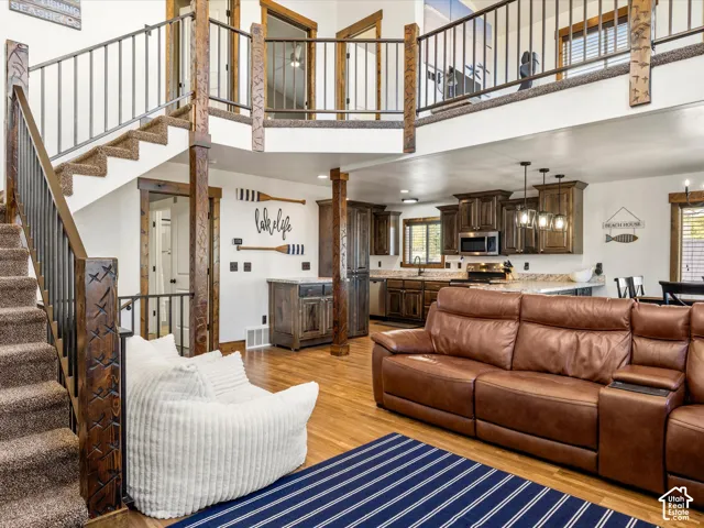 Open-concept living area featuring wood-finish flooring, a kitchen with dark cabinetry, granite-style countertops, and a two-story staircase with a wrought-iron railing