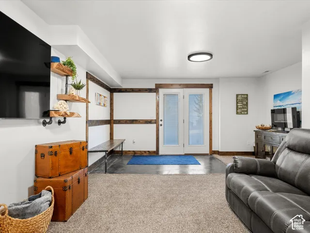 Basement family room.  Carpeted flooring, white walls, industrial-style shelving, and a double-door entry