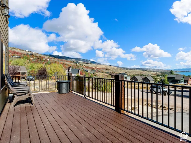 Main floor Deck with composite wood-finish flooring, black metal railings, and a detailed wall sconce