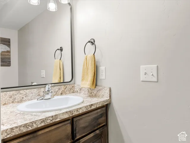 main floor 1/2-bath Vanity with a laminate countertop, integrated sink, and wood-finish cabinetry