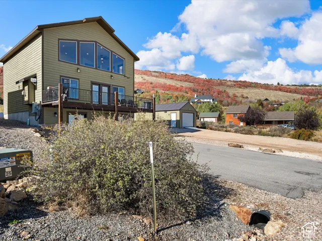 Multi-level exterior with siding, a large upper deck, and adjacent lot with storage garage