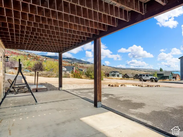 Covered concrete patio with exposed wood ceiling and mountain scenery