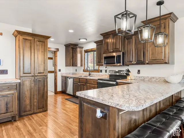 Kitchen featuring wood-finish cabinetry, stainless steel appliances, speckled countertops, and wood-finish flooring