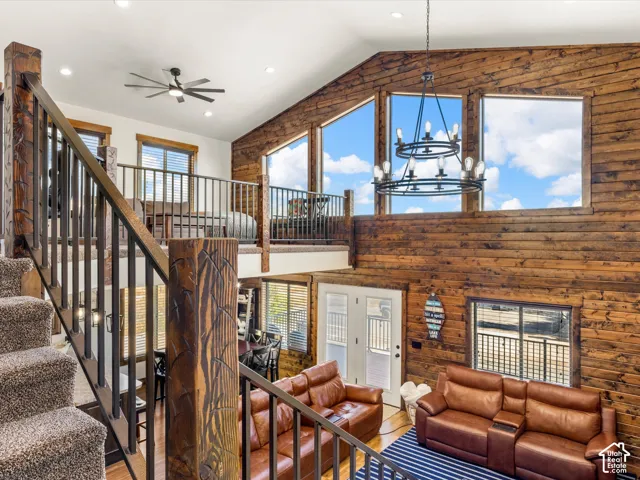 Vaulted ceilings with wood paneling, floor-to-ceiling windows, and a multi-tiered iron chandelier