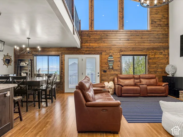 Hardwood flooring, wood-paneled accent wall, open-concept design, double-height ceilings, and multiple transom windows