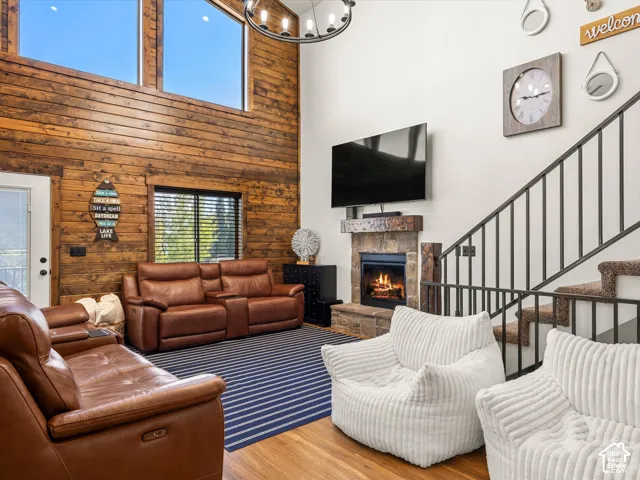 Vaulted ceilings with clerestory windows, wood-paneled accent wall, stone-clad fireplace, and wrought iron staircase railing