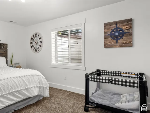 Basement bedroom.  Window with blinds providing natural light, white walls, and carpet flooring