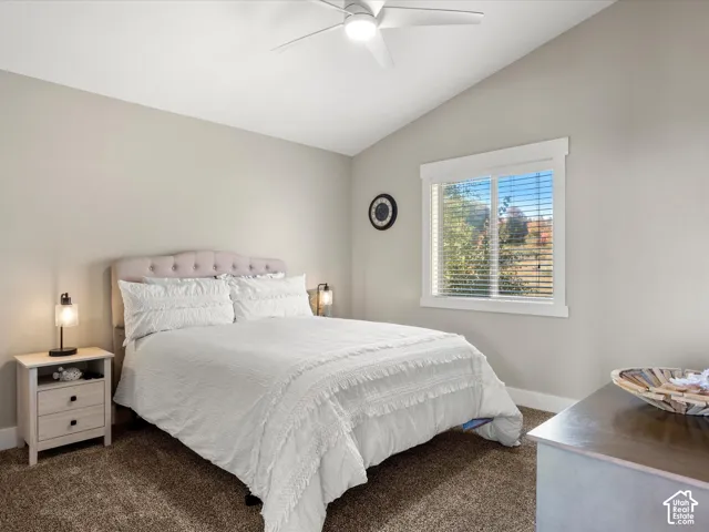 2nd floor bedroom. Vaulted ceiling with a ceiling fan, window with white blinds, upholstered headboard, and neutral wall tones