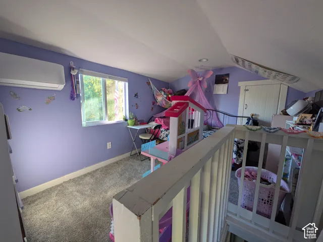 Carpeted room featuring a window, built-in air conditioning unit, and sloped ceiling