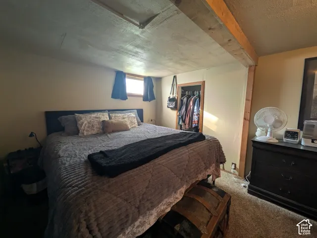 Exposed wood beam ceiling detail, recessed window, built-in closet with wood trim, and textured wall finish