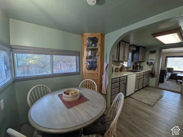 Wood-finish flooring throughout, featuring a kitchen with gray cabinetry, a built-in corner hutch, and an arched entry