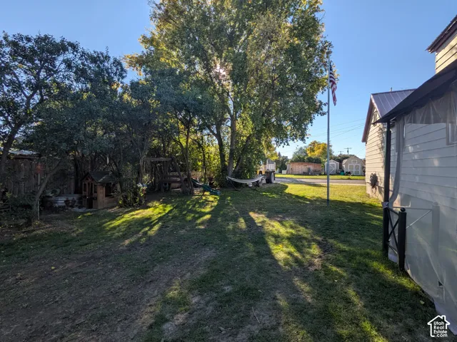 Expansive yard with mature trees, established lawn, and a light-colored siding exterior