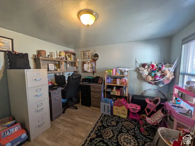 Primary Bedroom or office space. Wood-finish flooring with a ceiling-mounted light fixture