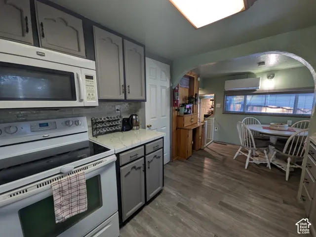 Kitchen featuring a built-in microwave, a tile backsplash, and light-toned cabinetry