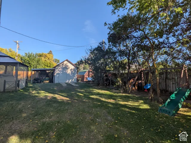 Spacious backyard featuring a storage shed, covered outdoor area, fenced perimeter, and mature trees