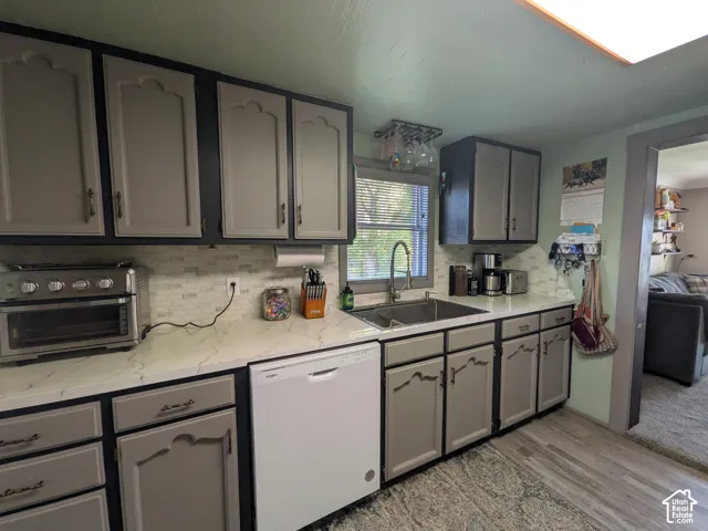 Kitchen featuring grey cabinetry with dark hardware, white countertops, tile backsplash, and wood-finish flooring