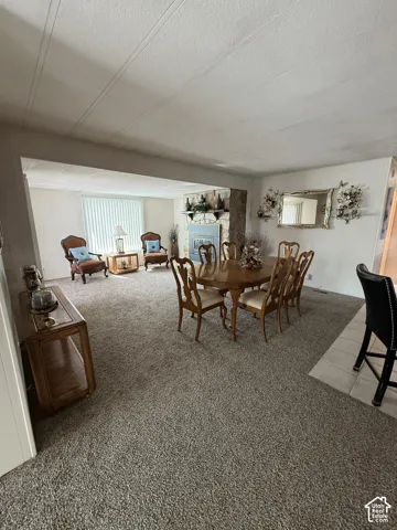 Open-concept living space featuring a natural stone fireplace, neutral carpeting, and a built-in shelf