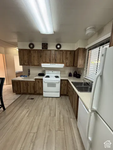Kitchen featuring wood-finish cabinetry, solid surface countertops, a double basin stainless steel sink, and wood-look flooring