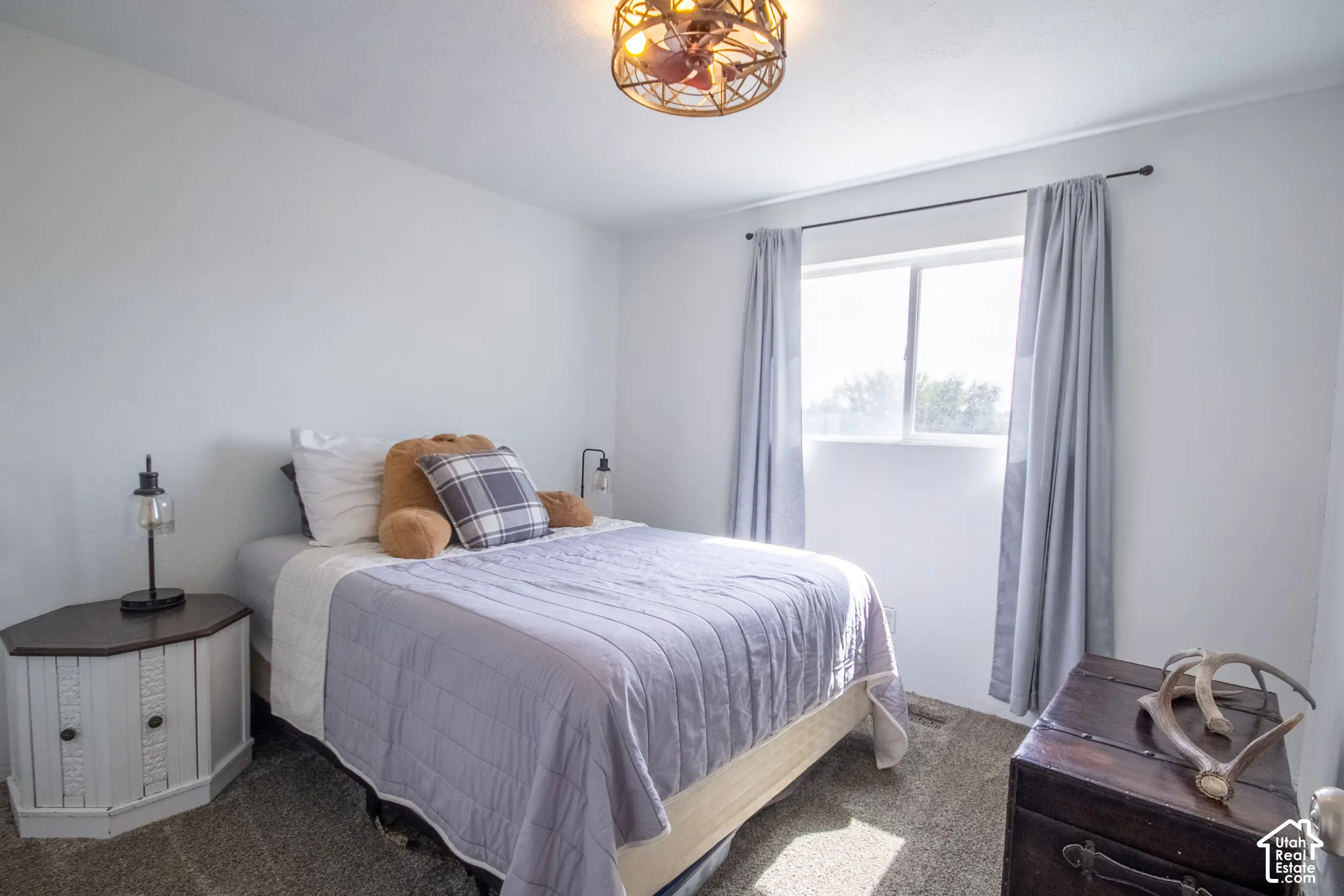 Light-colored walls, window with light-filtering curtains, and a ceiling-mounted light fixture