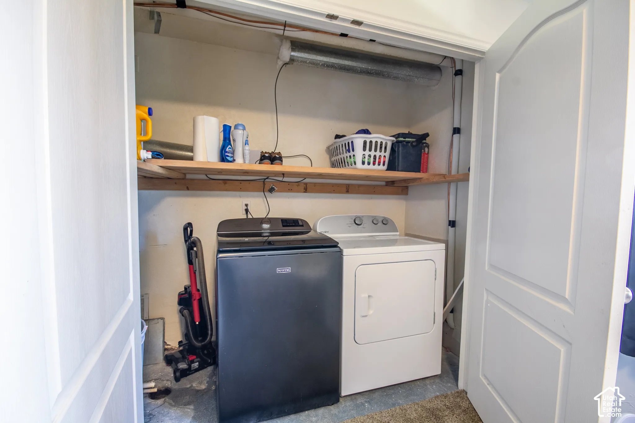 Dedicated laundry area featuring a washer and dryer, integrated shelving, and bi-fold doors