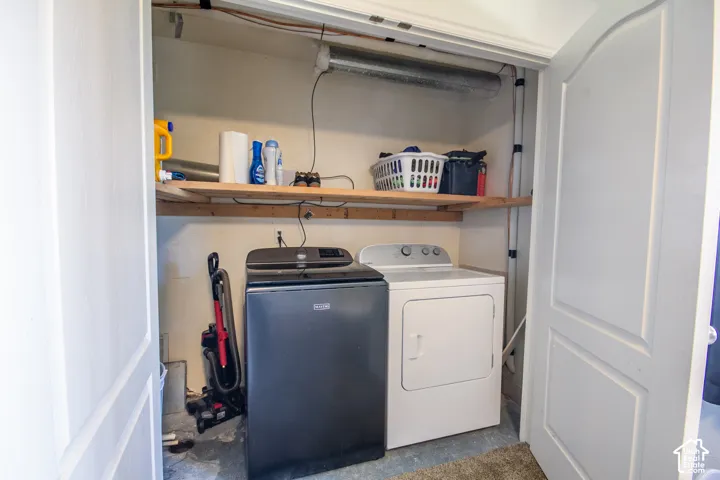 Dedicated laundry area featuring a washer and dryer, integrated shelving, and bi-fold doors