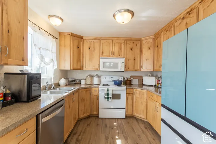 U-shaped kitchen featuring wood-finish cabinetry, built-in microwave, stainless steel dishwasher, and wood-finish flooring
