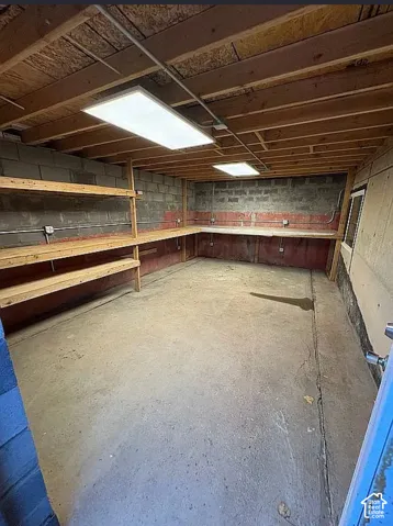 Concrete flooring, exposed joist ceiling, built-in shelving, built-in workbench, overhead lighting