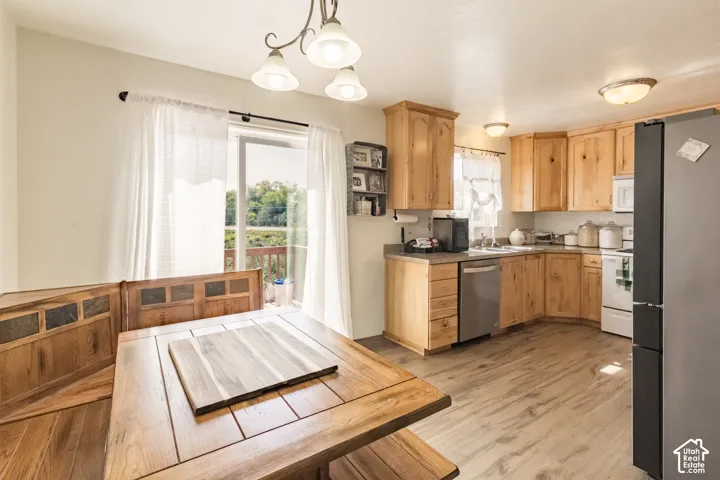 Kitchen featuring light wood-finish cabinetry, wood-finish flooring, stainless steel dishwasher, white range with overhead microwave, and granite-look countertops