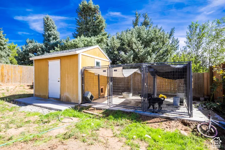 Backyard featuring a detached shed on a concrete pad, wood fence perimeter, and mature trees