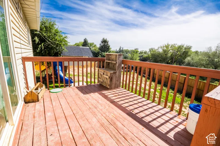 Wood-finish deck with a wood railing, siding exterior, and a sliding glass door