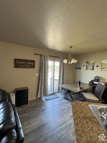 Wood-finish flooring, sliding glass door, pendant light fixture, and granite-look countertop