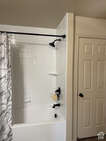 White subway tile surround with a built-in shelf, black-finish shower fixtures, and a white soaking tub