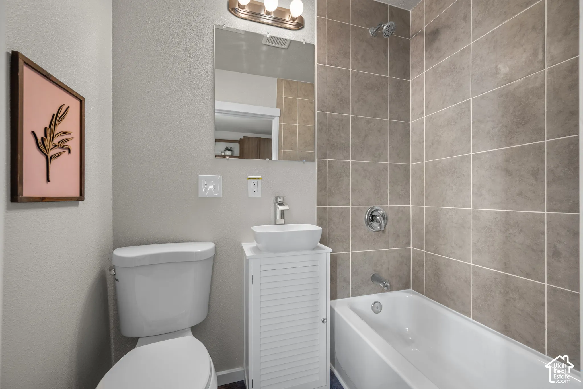 White freestanding vanity with a vessel sink, chrome faucet, and mirrored medicine cabinet