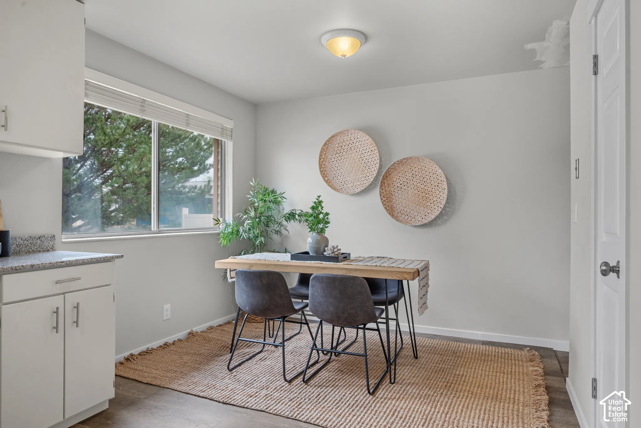 Recessed lighting, wood-finish flooring, white cabinetry with silver hardware, and a window with blinds