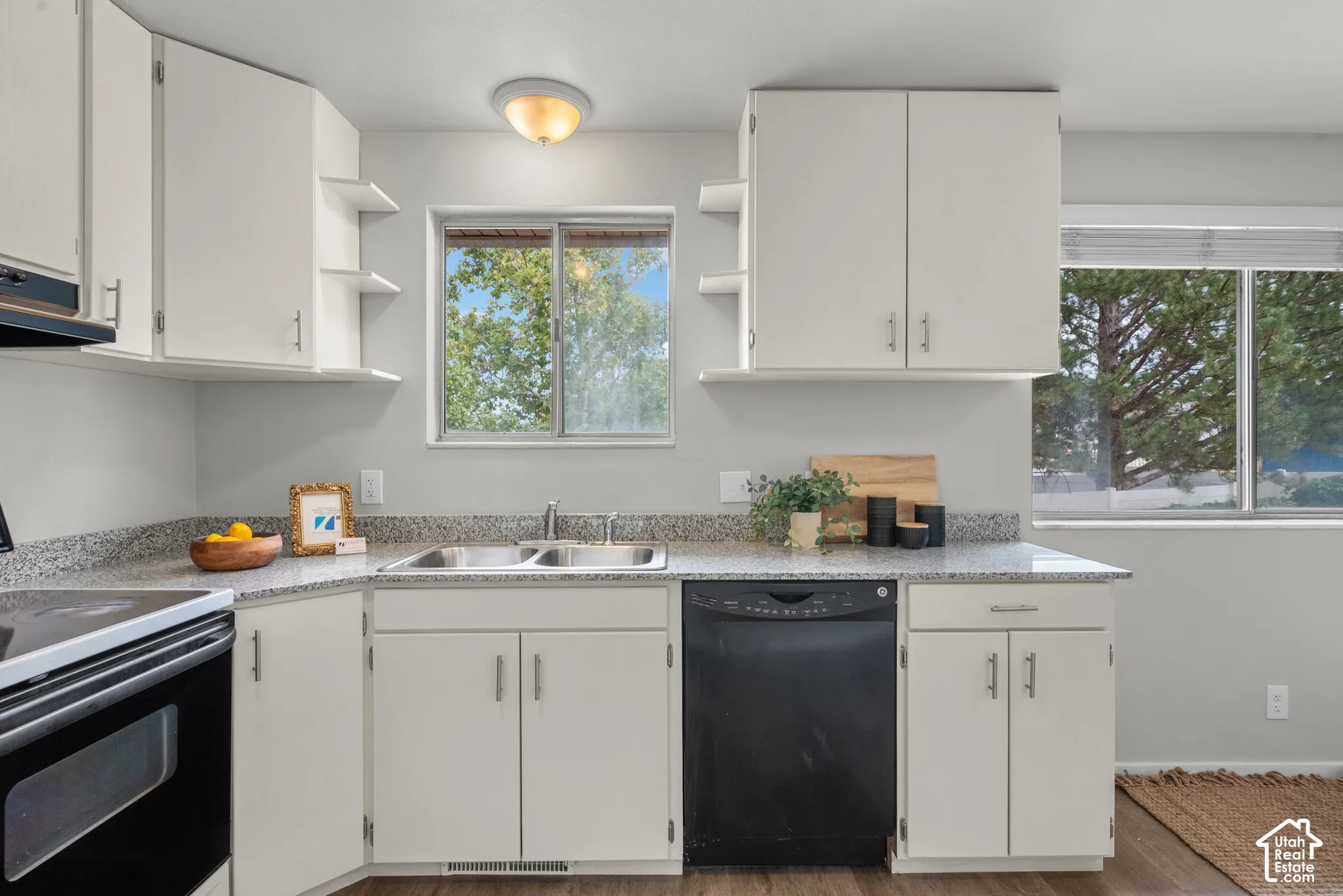 Kitchen featuring white cabinetry, speckled countertops, a double basin sink, and a black dishwasher