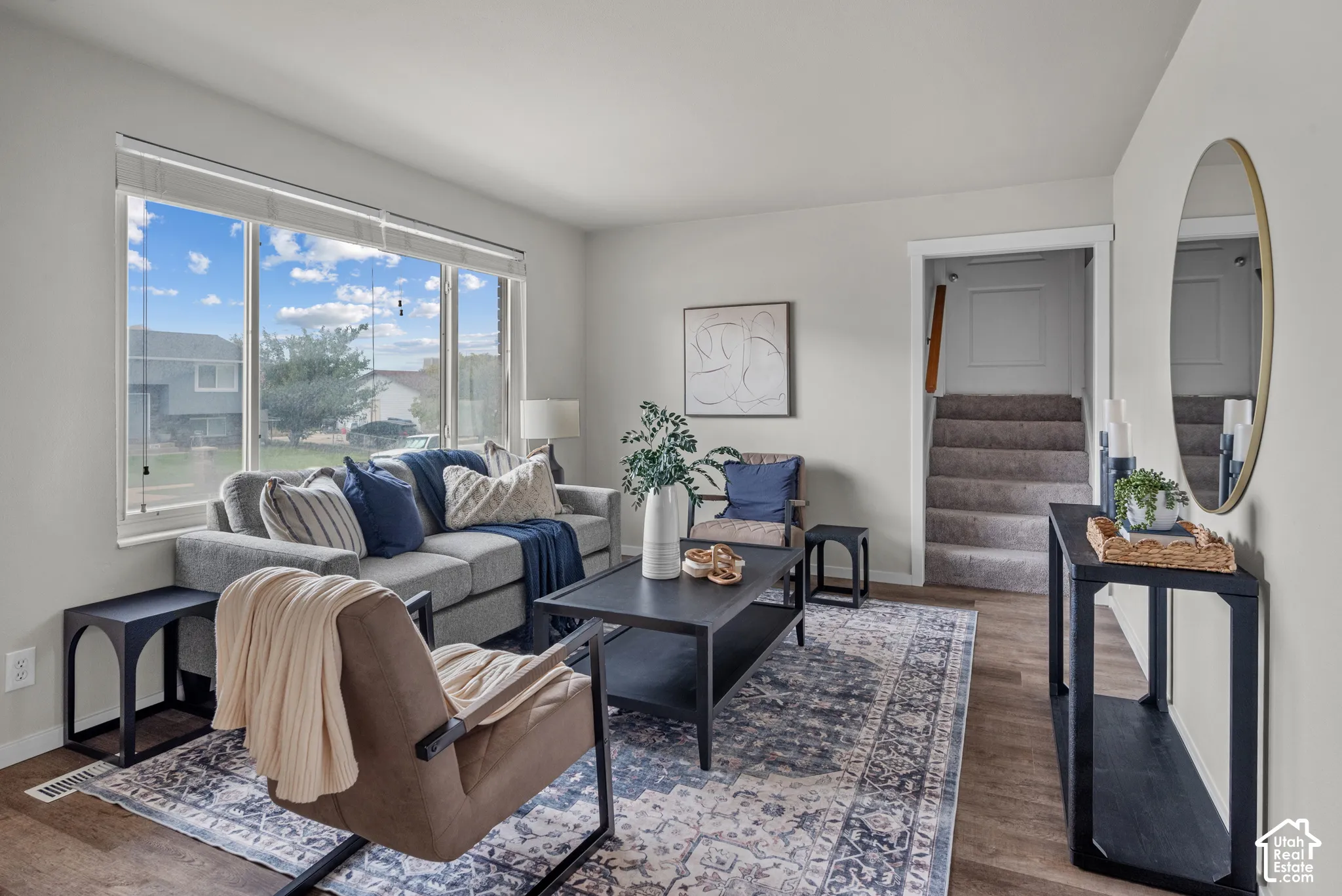 Spacious living area featuring large windows, wood-finish flooring, and light-toned walls
