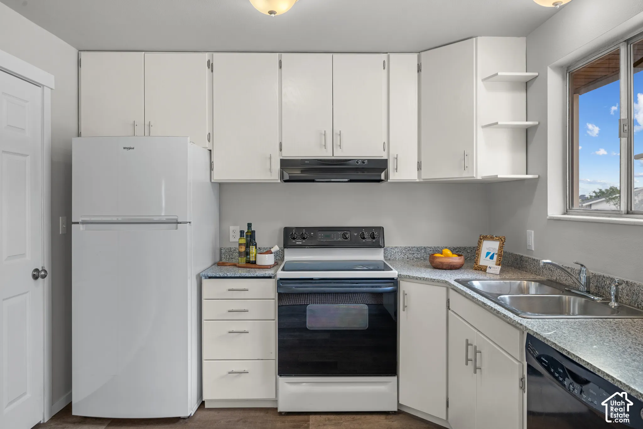 Kitchen featuring white cabinetry, grey speckled countertops, a double basin stainless steel sink, a black electric range, and a white refrigerator