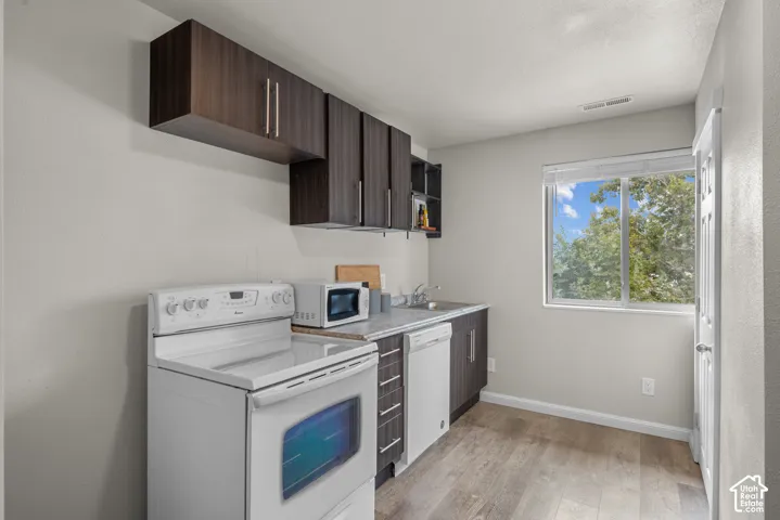 Wood-finish flooring, dark wood-finish cabinetry, and a white electric range