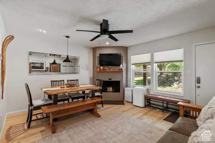 Light wood-finish flooring with a corner fireplace and a natural wood mantel