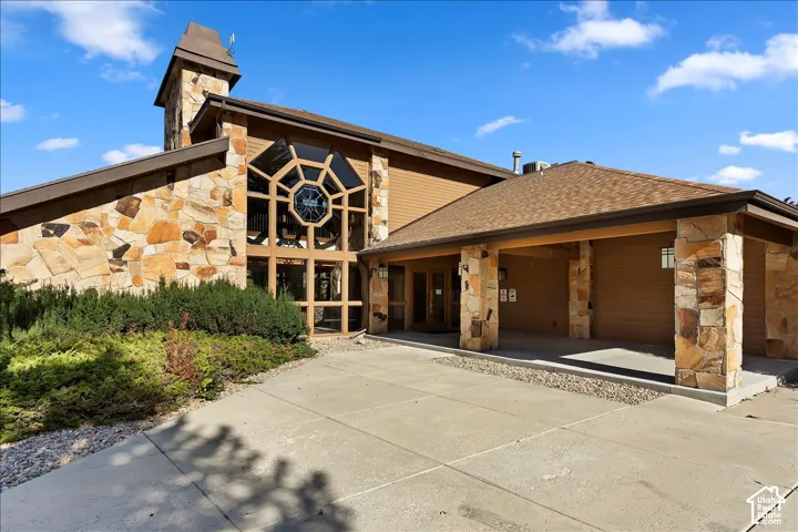 Stone veneer exterior with a prominent multi-paned window, covered entry, and pitched shingle roof