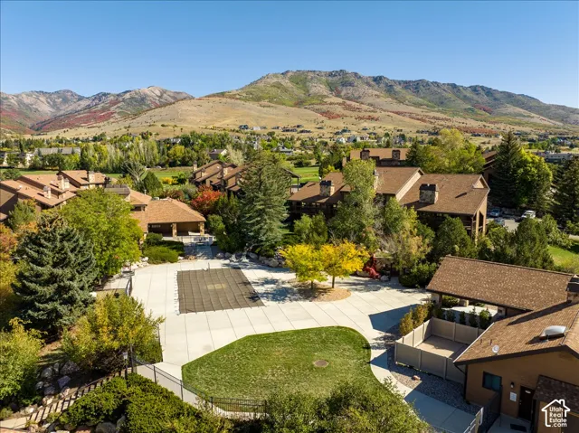 Mountain backdrop, covered outdoor pool, extensive hardscaping, mature trees, manicured lawn
