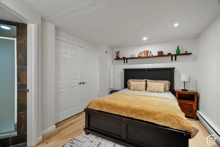 Hardwood-style flooring, recessed lighting, built-in shelving, two-panel closet doors, and a shower enclosure with natural stone-style tile