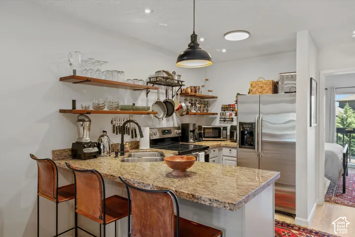 Kitchen featuring granite-style countertops, stainless steel appliances, a single-basin sink with a gooseneck faucet, and open wood shelving
