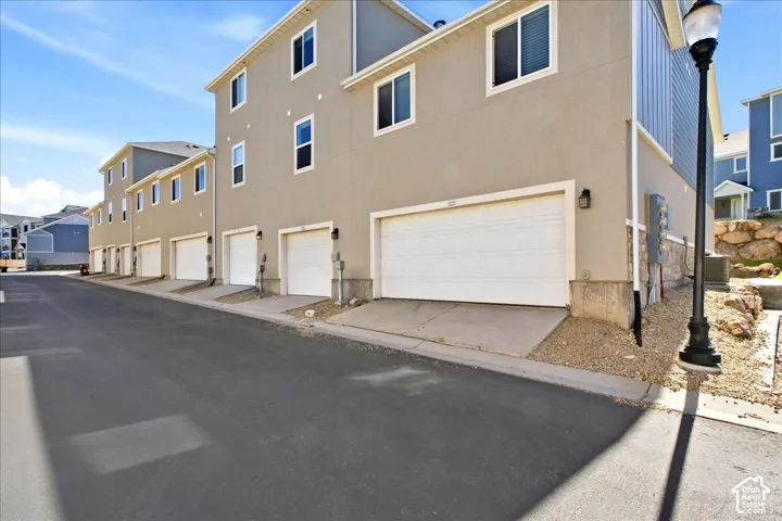 Stucco exterior with multiple windows, individual garage doors, and stone veneer accents