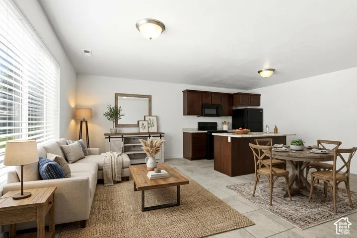 Open-concept living space featuring expansive windows, recessed lighting, a kitchen island with seating, dark wood-finish cabinetry, and stone-finish countertops