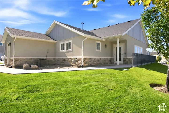 Exterior featuring stucco and stone-finish siding, a covered entrance, a sloped lawn, and a paved walkway