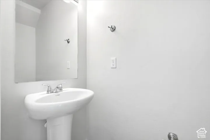 Pedestal sink with chrome faucet and rectangular wall mirror