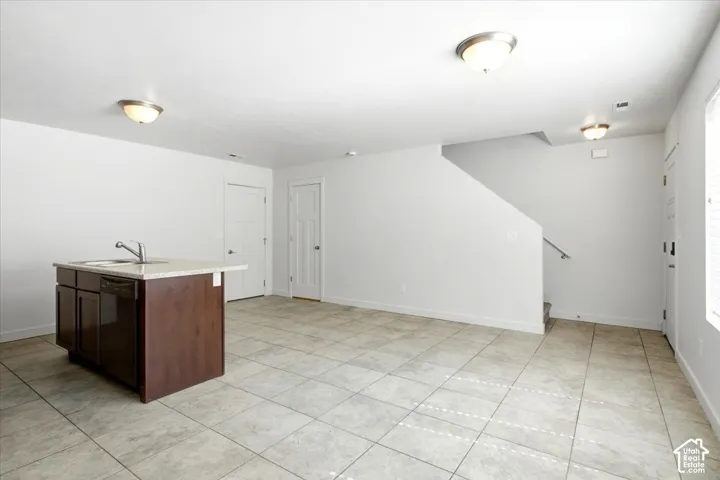Kitchen island with an undermount sink, built-in dishwasher, and light-toned countertop