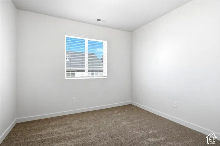 Neutral wall paint, carpet flooring, and a window with blinds